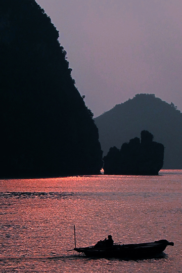 Sun silhouetting a sampan.