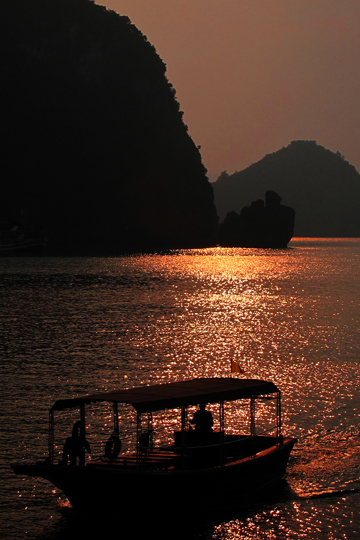 Sun silhouetting tourist vessels.