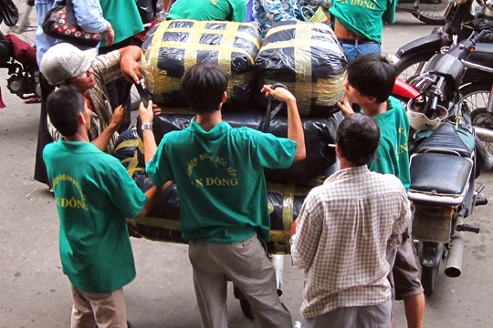 Loading a delivery-motorcycle. An Dong Market, Saigon.