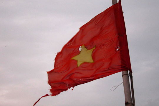 Tattered, wind-ripped flag, fishing village near Hoi An.