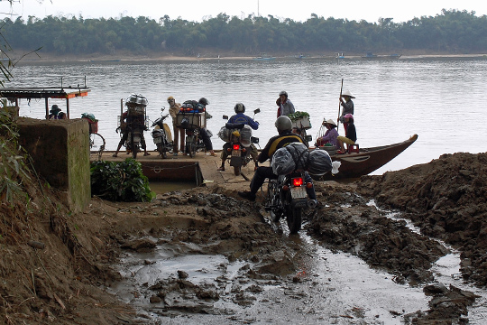 Mr. Tu and Duc riding the bikes onto the river-ferry, Central Highlands.