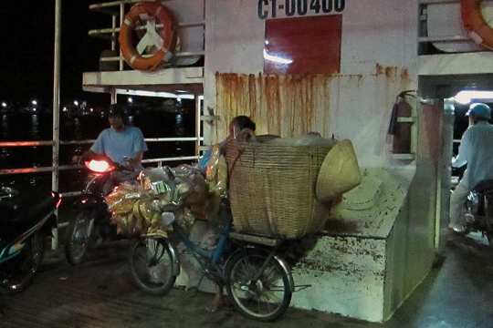 Motorcycles turn around beneath the bridge on the ferry, Can Tho.
