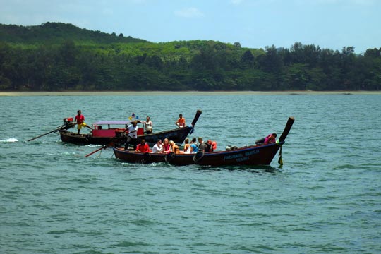 Longtail boats bringing passengers out to ferry.