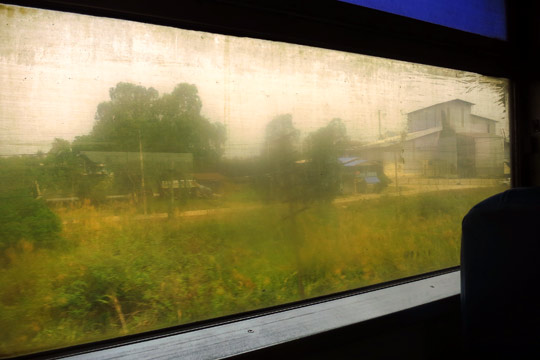 Country-side in motion through smokey haze and grimy windows.