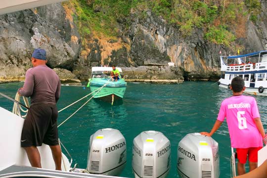 Tying off to another boat to let our swimmers into the water. The cave opening is just past the stern of the white vessel.